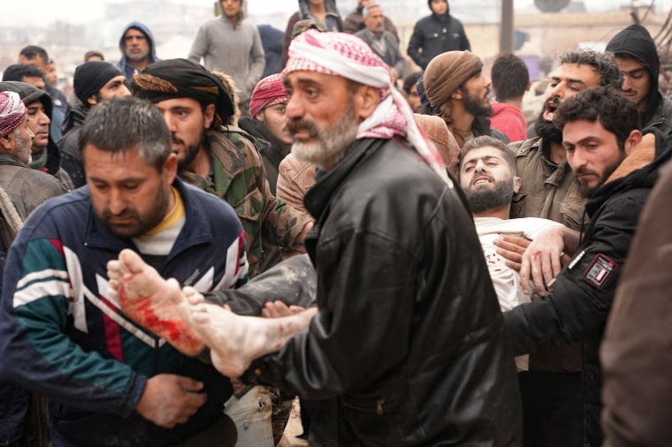 Residents retrieve an injured man from the rubble in Jandaris, Syria.