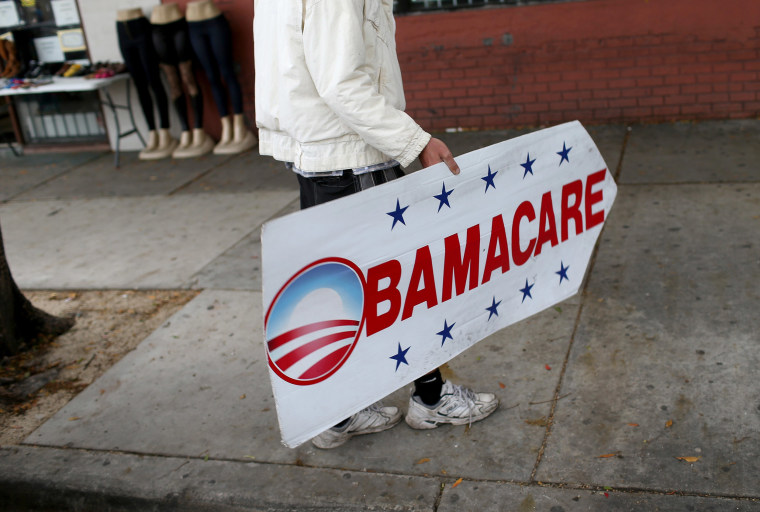 Image: Pedro Rojas holds a sign directing people to an insurance company where they can sign up for the Affordable Care Act, also known as Obamacare