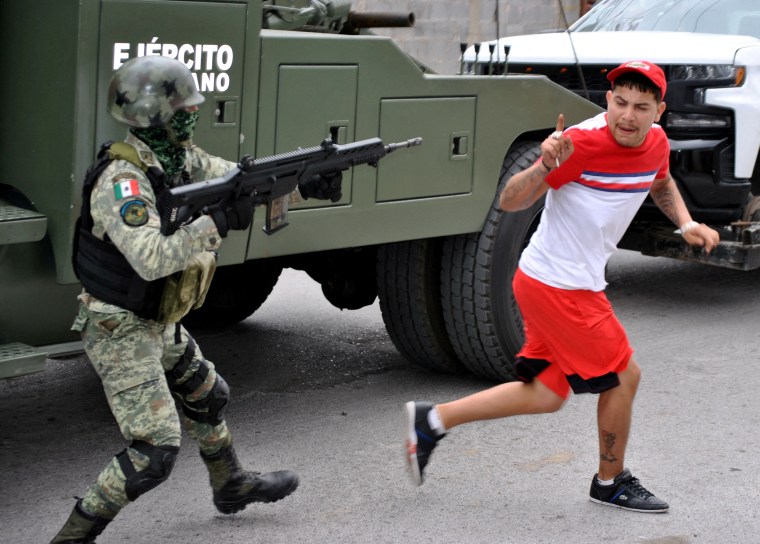 Un soldado mexicano apunta con su rifle a un hombre.