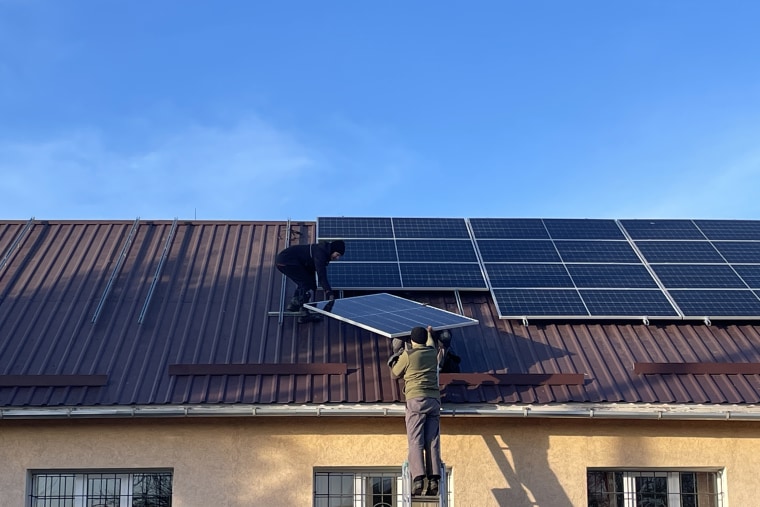Workers install solar panels at a hospital in Zviahel, Ukraine.