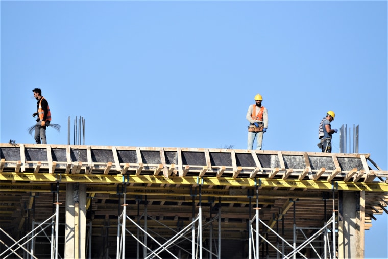 Des ouvriers du bâtiment se tiennent au dernier étage d'un immeuble en construction pendant leur quart de week-end à Ankara le 22 avril 2018.
