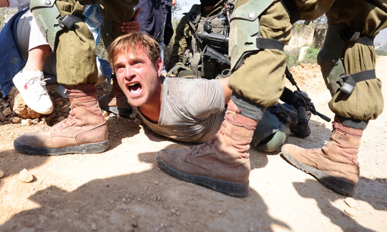 Israeli security forces arrest an Israeli peace activist at the entrance of the West Bank town of Hawara,