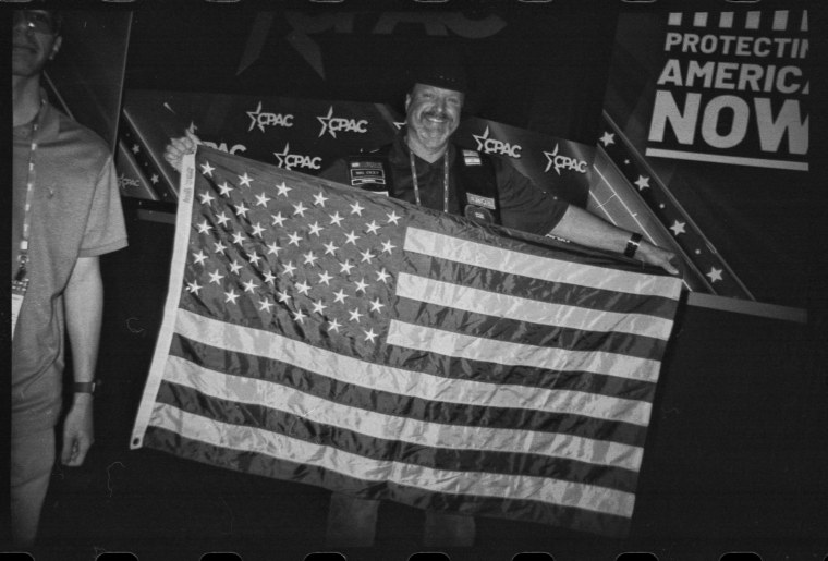 An attendee holds up an American flag in the main hall of CPAC after a speech in National Harbor, Md., on March 3, 2023.