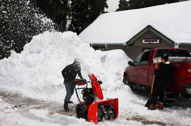Residents clear a driveway after a series of winter storms dropped more than 100 inches of snow in the San Bernardino Mountains
