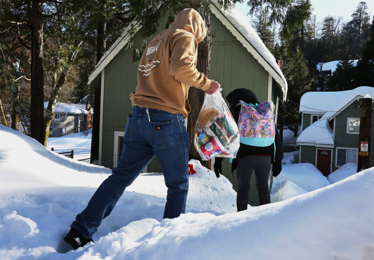 A resident carries a bag of donated food items home after a series of winter storms