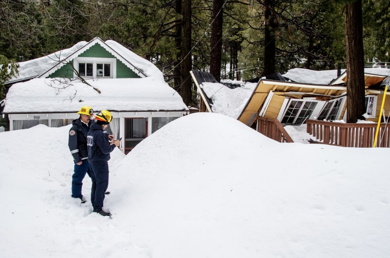Fire crews document the damage of a house with a collapsed roof in Crestline, Calif.