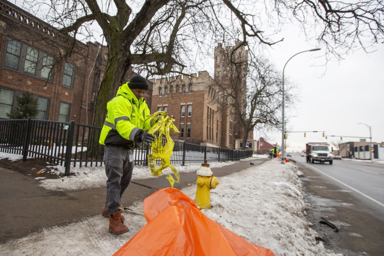 A City of Rochester employee cleans up police tape outside of the Main Street Armory 