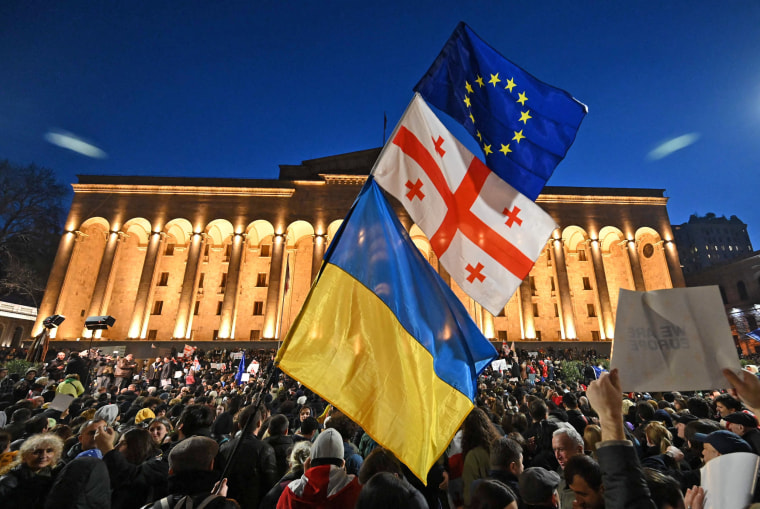 Protesters wave the Georgian, Ukrainian and European flags outside Georgia's Parliament in Tbilisi on March 8, 2023.