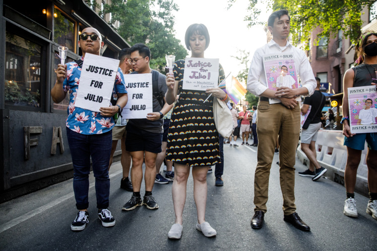 People hold signs for a vigil commemorating Julio Ramirez