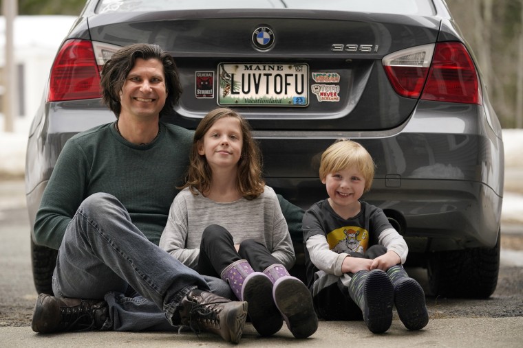 Peter Starostecki and his kids Sadie, center, and Jo Jo, behind their car with the vanity license plate that the state of Maine has deemed in appropriate, in Poland, Maine