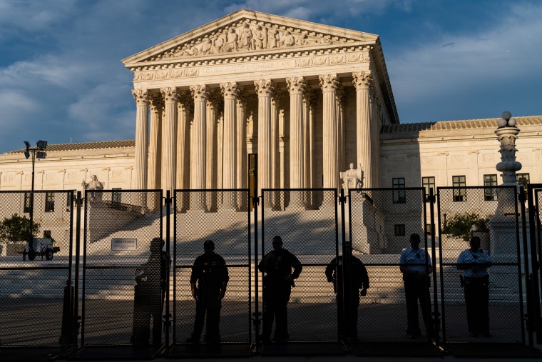 Law enforcement officers watch protesters from behind security fencing near the Supreme Court on June 27, 2022.