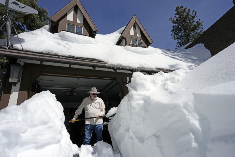John Bays clears snow off his driveway after a series of storms, in Lake Arrowhead, Calif.