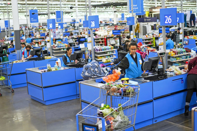 Cashiers process purchases at a checkout line at a Walmart Supercenter