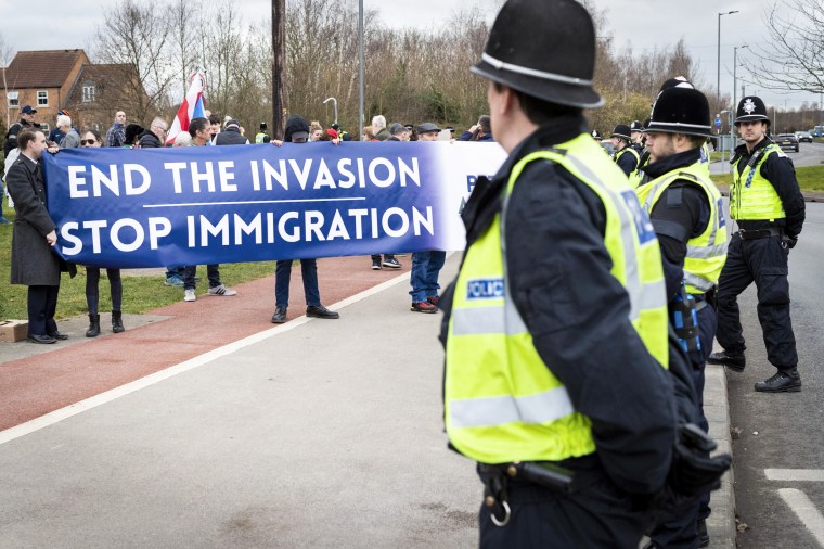 Anti-immigration protesters hold a banner outside the Holiday Inn hotel housing refugees in Rotherham, England, on February 18, 2023.