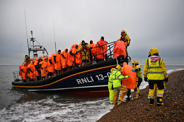 Des migrants, récupérés en mer alors qu'ils tentaient de traverser la Manche, sont aidés à débarquer d'un canot de sauvetage de la Royal National Lifeboat Institution, à Dungeness, sur la côte sud-est de l'Angleterre, le 9 décembre 2022.