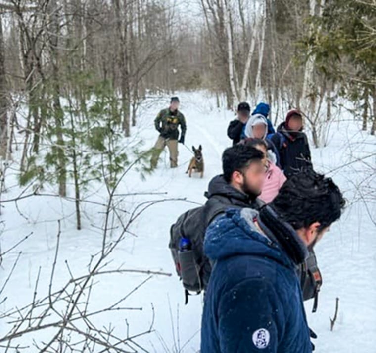 A U.S. Border Patrol agent apprehends seven Mexican citizens near Mooers, N.Y., who had crossed into the U.S. from Canada illegally on March 7, 2023.