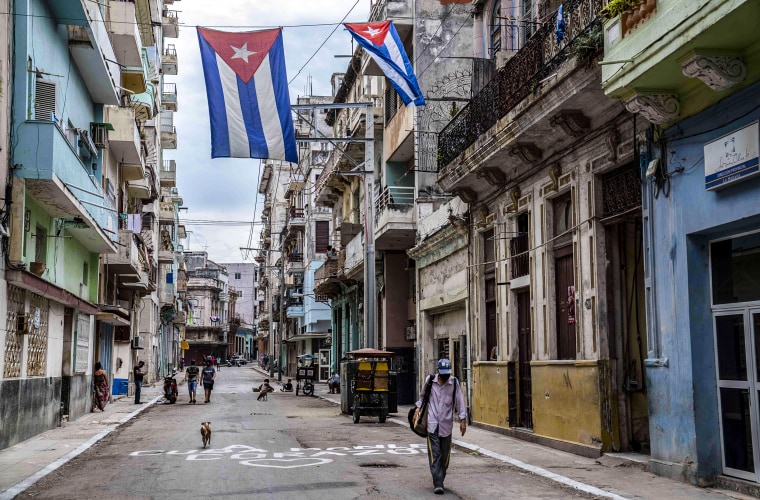 A man walks under Cuban flags flying over a street in Havana on July 26, 2021.