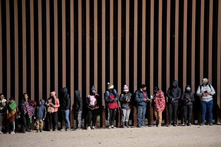 Asylum-seekers line up to be processed by U.S. Customs and Border Patrol agents at a gap in the US-Mexico border fence near Somerton, Ariz., on Dec. 26, 2022.