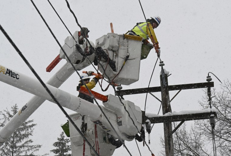 National Grid lineman Jim Sheeran, top, and Matthew Jukes fix a primary power line during a winter snow storm in Ballston Lake, N.Y.