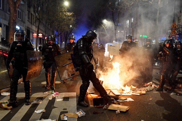 A French gendarme starts a street fire during a demonstration in Paris