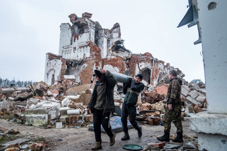 Volunteers carry remains of a Uragan rocket after a monastery was destroyed in a shelling in Dolyna, Ukraine