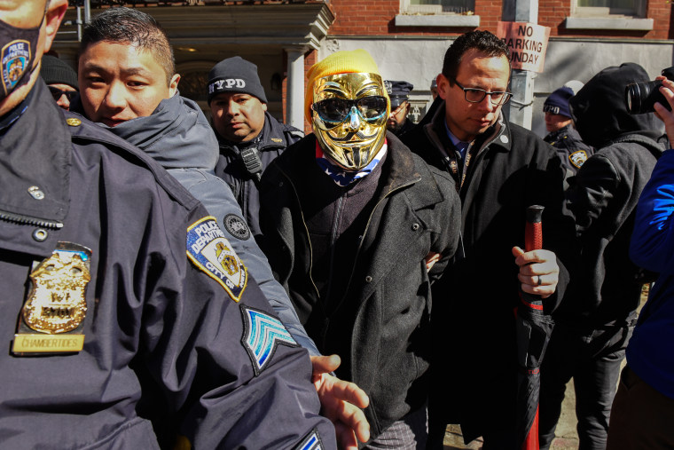  A man in a gold Anonymous mask is detained at a protest against Drag Queen story hour outside of The Center, a support space for LGBTQ+ people on March 19, 2023 in New York City. 