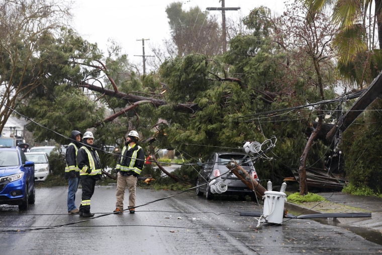 Emergency personnel look at damage to a utility pole after tree damage during a storm in Santa Rosa, Calif.