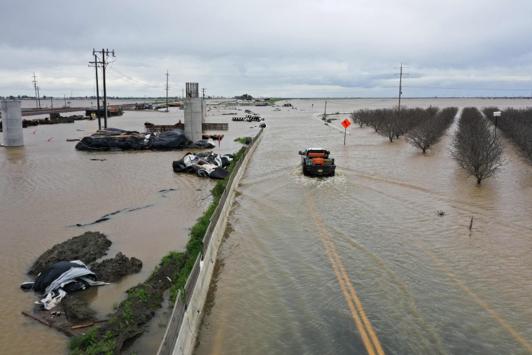 A truck drives across a flooded road near Corcoran, Calif.