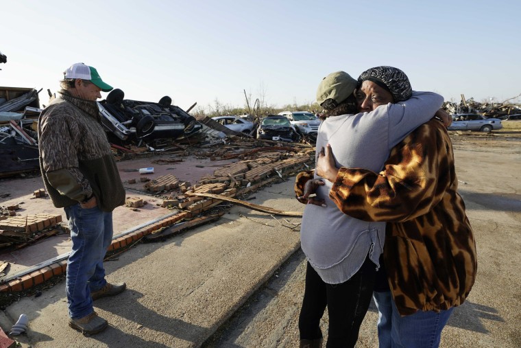 Tracy Hardin, center, who with her husband Tim, left, consoles a neighbor in Rolling Fork, Miss.