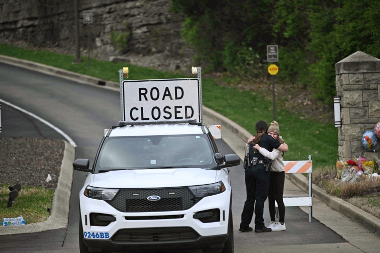 A woman hugs a police officer at the entrance of the Covenant School in Nashville, Tenn., on March 28, 2023.