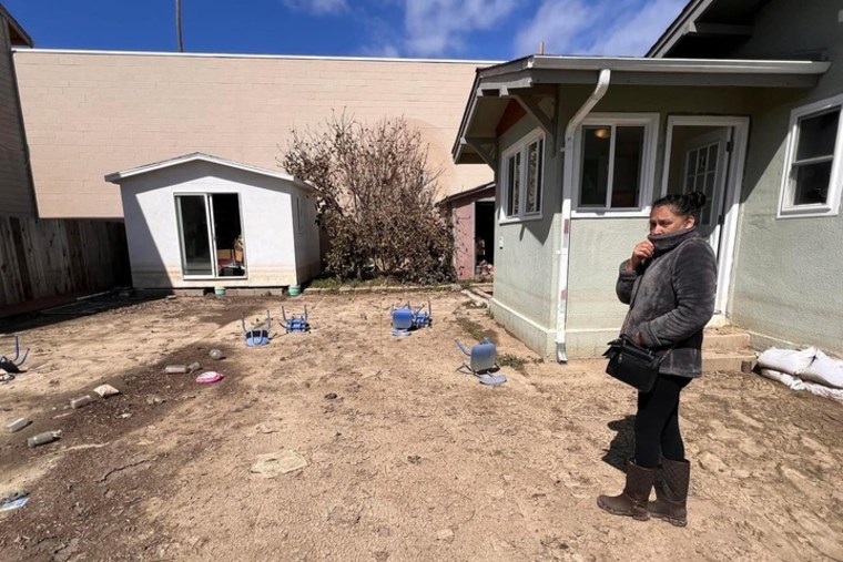 Maria Urbieta reviews the outside of her home where there was once a fence in Pajaro, Calif., on March 23, 2023.