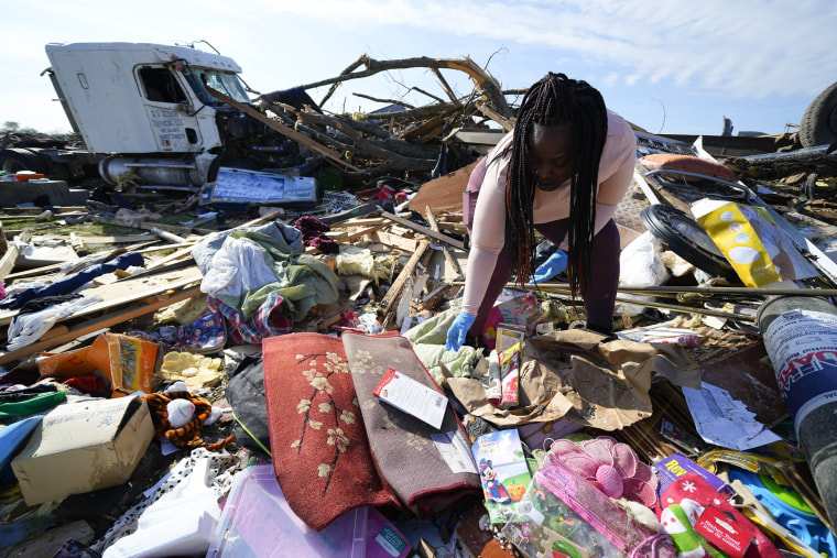 Kimberly Patton surveys through the belongings at the spot of a family member's home on March 26, 2023, in Rolling Fork, Miss. 