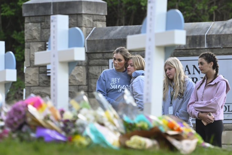 Students at a nearby school pay respects at a memorial for victims at an entry to Covenant School