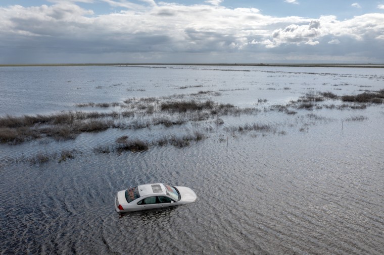 A car is left stranded on a flooded road near Corcoran, Calif.,