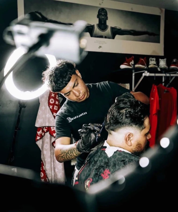 Carlos Flores, barbero en la ciudad de Kyle, Texas, trabaja con un cliente. 