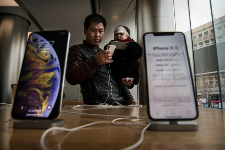 Un hombre chino sostiene a su hijo mientras miran iPhones en exhibición en una Apple Store en Beijing, China, el 7 de enero de 2019.