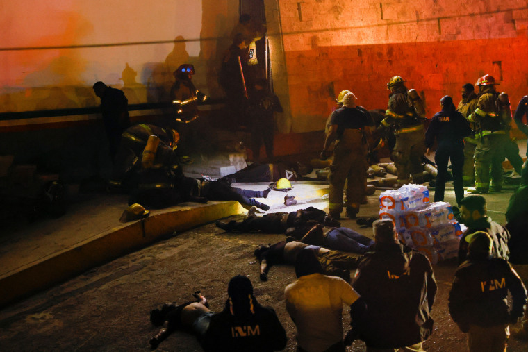 Autoridades mexicanas y bomberos junto a cadáveres, mientras sacan a migrantes heridos, en su mayoría venezolanos, del interior del edificio del Instituto Nacional de Migración (INM) durante un incendio, en Ciudad Juárez, México 27 de marzo de 2023. 