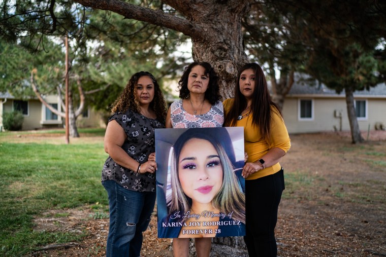 Feliz Sánchez-García y Mileiah Rodríguez son fotografiadas con su madre Debby García mientras sostienen una foto de su hija Karina Rodríguez, víctima de una sobredosis, afuera de su casa en Denver, Colorado, el jueves 29 de septiembre de 2022.
