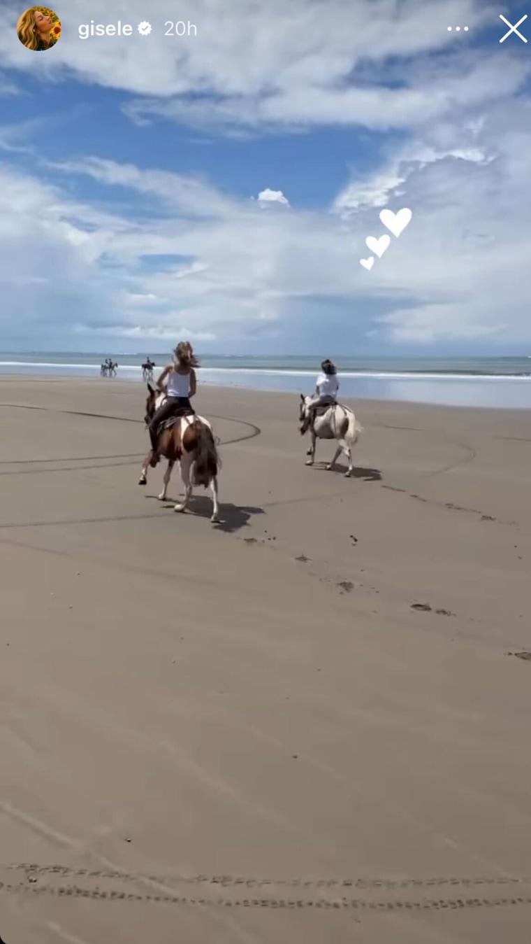 Gisele riding horses with daughter Vivian on a beach.