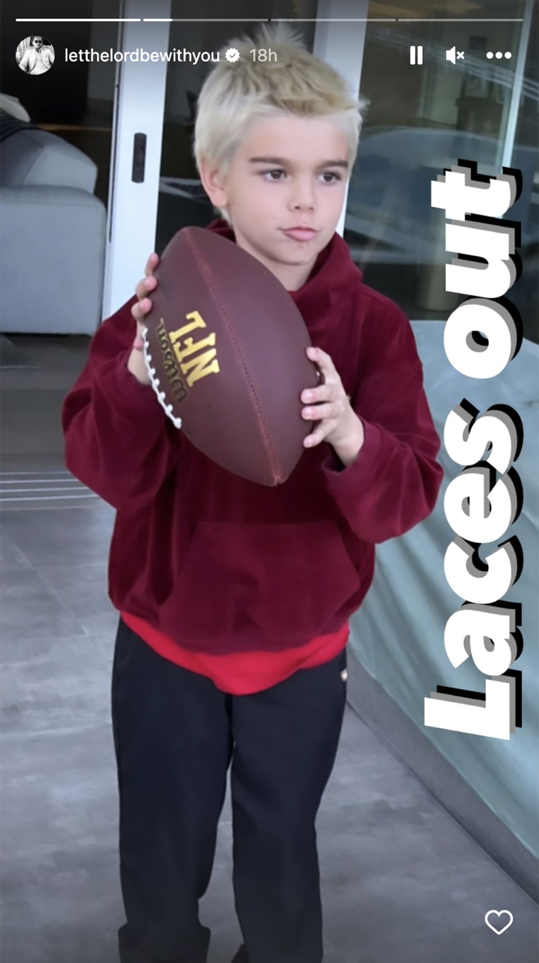Reign, now with blond hair, poses with a football