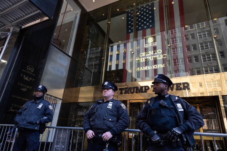 Los miembros de la policía de Nueva York se paran frente a la Torre Trump, que fue rodeada por vallas tras conocerse la acusación. 