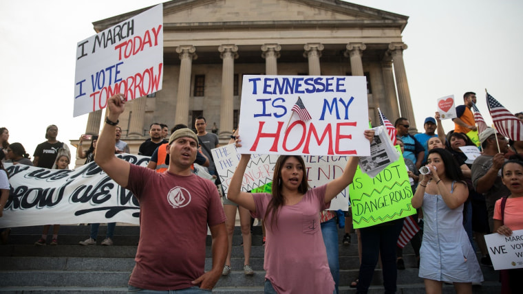 Un grupo de personas sosteniendo carteles que dicen "Tennessee es mi hogar" y "hoy marcho, mañana voto" protestan frente al edificio del Capitolio estatal de TN en 2018