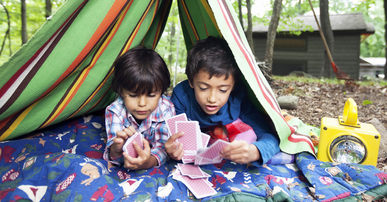 Boys playing card game in blanket fort