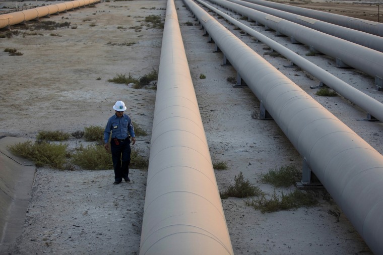 An employee walks along a pipeline carrying crude oil from the Juaymah Tank Farm in Saudi Aramco's Ras Tanura oil refinery in Ras Tanura, Saudi Arabia, on Oct. 1, 2018.