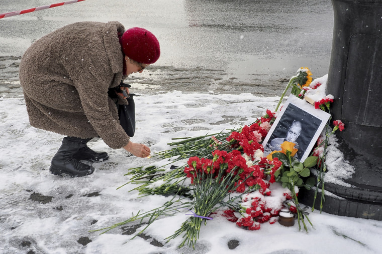 A womam lights a candle at a memorial for Vladlen Tatarsky at the Street Bar cafe in St. Petersburg, Russia.