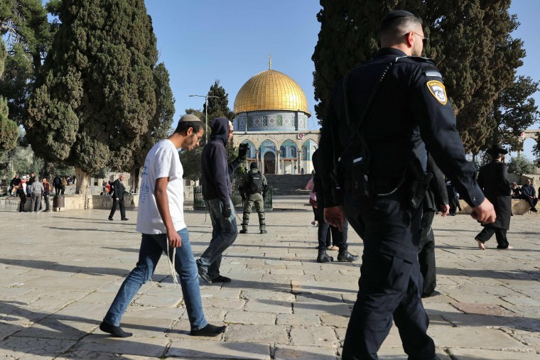 Jewish worshippers walk protected by Israeli security forces at the Al-Aqsa mosque compound in Jerusalem, early on April 5, 2023 during Islam's holy month of Ramadan. - Israeli police said they had entered to dislodge "agitators", a move denounced as an "unprecedented crime" by the Palestinian Islamist movement Hamas. 