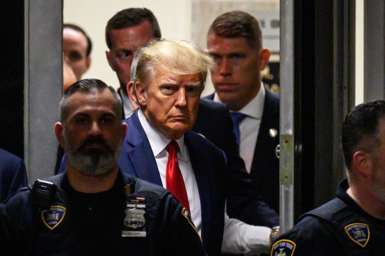Former US President Donald Trump walks with security personnel as he makes his way inside the Manhattan Criminal Courthouse