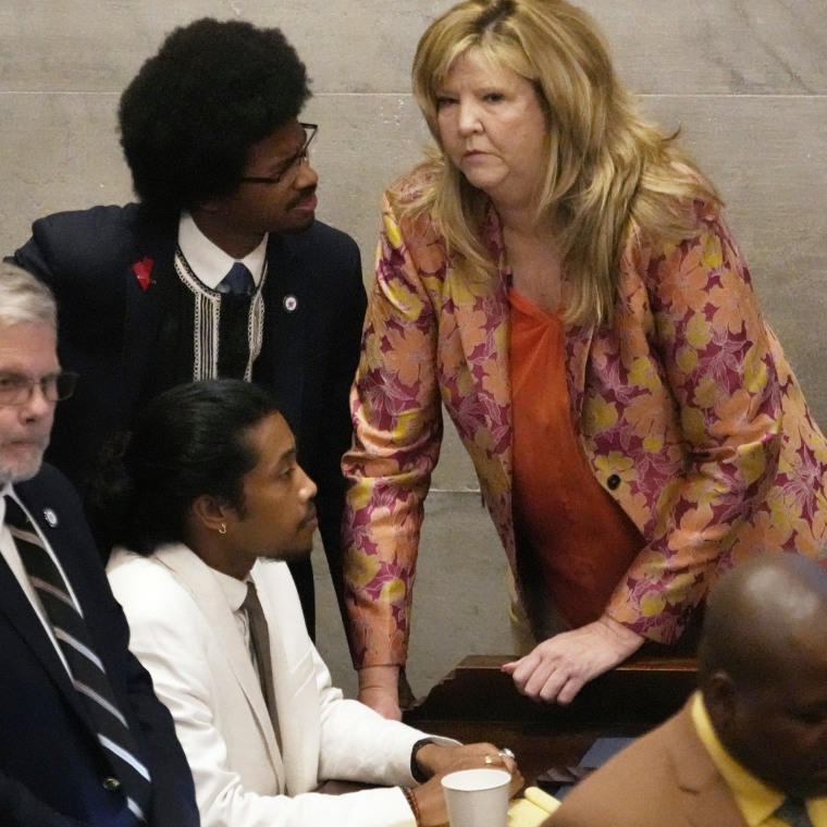 Rep. Justin Jones, D-Nashville, seated in white suit, Rep. Justin Pearson, standing top left, D-Memphis, and Rep. Gloria Johnson, D-Knoxville, huddle on the floor of the House chamber in Nashville, Tenn., on April 6, 2023.