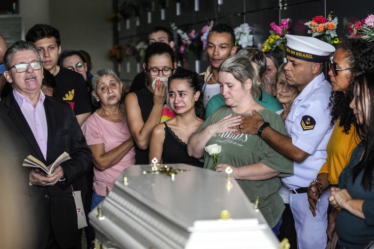 Image: Bruno Machado, right, and his wife Neide Cunha, center, mourn at the funeral of their five-year-old son Bernardo who was killed by a man with a hatchet inside a day care center, at the Sao Jose cemetery in Blumenau, Santa Catarina state, Brazil, on April 6, 2023. 