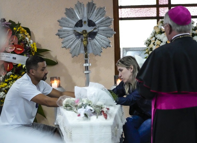 Image: Parents sit next to the coffin which contains the remains of their seven-year-old daughter, Larissa Maia Toldo, who was killed by a man with an outbreak inside a daycare centre, during a wake at the Sao Jose cemetery, in Blumenau, Santa Catarina State, Brazil, on April 6, 2023.